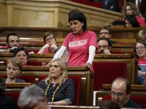 FILE - In this April 7, 2016 file photo, Anna Gabriel, deputy of anti-capitalist Candidatura d'Unitat Popular (CUP) speaks wearing a t-shirt that reads in Catalan: "Without Fear, We disobey for the independence" during a debate of the plenary of the Parliament of Catalonia in Barcelona, Spain. Anna Gabriel, the leader of the anti-establishment Catalan CUP party, is vowing to carry on advocating for Catalan independence from her current base in Switzerland where she is evading a Spanish judicial probe for her role in last year's illegal secession attempt.