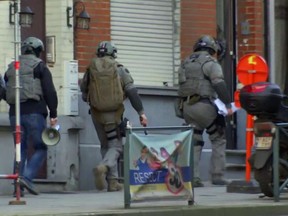 Belgium security personnel enter a building in Brussels in this image taken from TV Thursday Feb. 22, 2018. Belgian police have sealed off part of a Brussels suburb amid media reports that an armed man could be at large. (AP Photo)