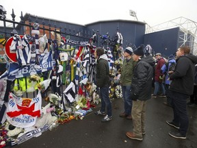 Fans look at tributes to late international soccer playerCyrille Regis ahead of the English Premier League soccer match at The Hawthorns, West Bromwich, England, Saturday Feb. 3, 2018.  Regis died Jan. 14, 2018.
