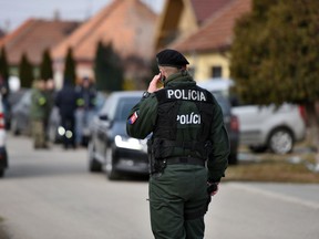 In this photo taken on Monday, Feb. 26, 2018, police stand outside the site of a murder in the village Velka Maca, Slovakia. A leading Slovak newspaper says organized crime may have been involved in the shooting death of an investigative journalist that shocked Slovakia. The bodies of 27-year-old Jan Kuciak and his girlfriend Martina Kusnirova were found Sunday evening in their house in the town of Velka Maca, east of the capital, Bratislava.