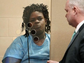 FILE - In this Feb. 6, 2018 file photo, Latarsha Sanders, 43, is arraigned in Brockton, Mass., District Court on two counts of murder, standing with her defense attorney Joseph Krowski, Jr., right. When asked by police why she stabbed her older son, Latarsha Sanders told police "it was because of the voodoo stuff," according to court documents. But practitioners of Haitian Vodou said the religion doesn't sanction violence and fear the incidents will spark a backlash against their community.