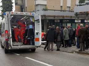 Paramedics, background center, attend a wounded man after a shooting broke out in Macerata, Italy, Saturday, Feb. 3, 2018. Italian police arrested a lone gunman in a series of drive-by shootings targeting foreigners Saturday morning that paralyzed a small central Italian city still reeling from the gruesome murder of a young Italian woman allegedly at the hands of a Nigerian immigrant.