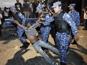 FILE- In this Feb. 2, 2018, file photo, Maldivian police officers detain an opposition protestor demanding the release of political prisoners during a protest in Male, Maldives. As a political crisis plays out in the Maldives, a quiet tug of war is taking place around it, with regional heavyweights China and India vying for strategic dominance in the picturesque Indian Ocean nation.
