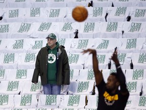 A fan watches warmups amid seats draped with T-shirts with retired Boston Celtics jersey numbers before an NBA basketball game against the Cleveland Cavaliers in Boston, Sunday, Feb. 11, 2018. The Celtics will retire Paul Pierce's No. 34 after the game.