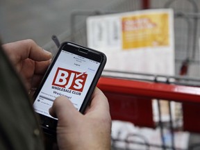 In this Tuesday, Feb. 13, 2018 photo Tony D'Angelo logs into the stores Wi-Fi to download the BJ's Express Scan app on his cell phone before beginning his shopping at the BJ's Wholesale Club in Northborough, Mass. More stores are letting customer tally their choices with a phone app or store device as they roam the aisles. For customers, scanning as they go can be faster and make it simpler to keep track of spending.
