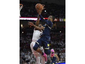 Michigan guard Muhammad-Ali Abdur-Rahkman, right, goes to the basket against Maryland guard Dion Wiley, left, during the first half of an NCAA college basketball game, Saturday, Feb. 24, 2018, in College Park, Md.