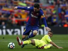FC Barcelona's Lionel Messi, top, duels for the ball against Getafe's Mathieu Flamini during the Spanish La Liga soccer match between FC Barcelona and Getafe at the Camp Nou stadium in Barcelona, Spain, Sunday, Feb. 11, 2018.