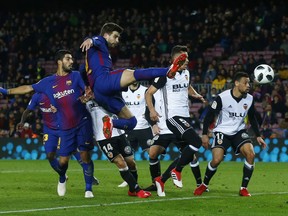 FC Barcelona's Gerard Pique, center, kicks the ball during the Spanish Copa del Rey, semifinal, first leg, soccer match between FC Barcelona and Valencia at the Camp Nou stadium in Barcelona, Spain, Thursday, Feb. 1, 2018.
