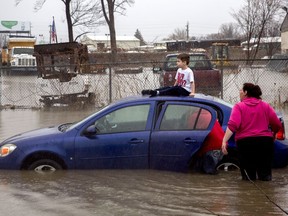 Flint resident Brayden Bend, 5, sits on top of his mother's friend's vehicle on Robert T. Longway Boulevard at North Center Road on Tuesday, Feb. 20, 2018, in Flint, Mich. High flood waters caused several motorists to become stuck.