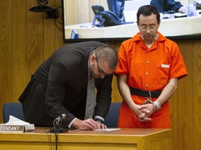 FILE- In this Feb. 5, 2018 file photo, Defense attorney Matthew Newberg, left, signs court documents after Judge Janice Cunningham sentenced Larry Nassar, right, at Eaton County Circuit Court in Charlotte, Mich. After #MeToo erupted from sexual assault and harassment claims against movie producer Harvey Weinstein, former sports doctor Larry Nassar's sexual assault sentencing this year became its own powerful forum for speaking out.