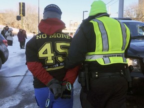 A transit police officer escorts a protester away after protesters formed a human blockade Sunday, Feb. 4, 2018, across light-rail tracks near U.S. Bank Stadium in Minneapolis where the Super Bowl between the New England Patriots and the Philadelphia Eagles was scheduled to kick off later in the evening.