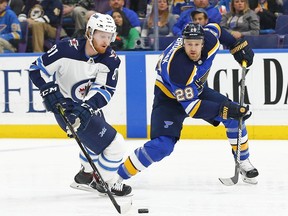 Winnipeg Jets' Kyle Connor, left, handles the puck as he is pressured by St. Louis Blues' Kyle Brodziak during the first period of an NHL hockey game Friday, Feb. 23, 2018, in St. Louis.