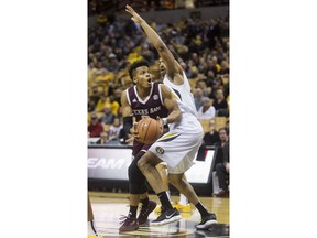 Texas A&M's Admon Gilder, left, dribbles around Missouri's Jordan Barnett, right, as he shoots during the first half of an NCAA college basketball game Tuesday, Feb. 13, 2018, in Columbia, Mo.