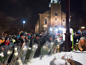People place flowers during a vigil to commemorate the one-year anniversary of the Quebec City mosque shooting, in Quebec City, Jan. 29, 2018.