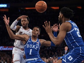 St. John's Shamorie Ponds, left, passes the ball in between Duke's Trevon Duval, center, and Marques Bolden, right, during the first half of an NCAA college basketball game at Madison Square Garden in New York, Saturday, Feb. 3, 2018.