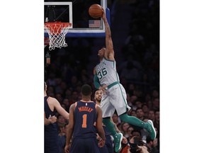 Boston Celtics guard Marcus Smart (36) dunks over New York Knicks guard Emmanuel Mudiay (1) and other Knicks during the first half of an NBA basketball game in New York, Saturday, Feb. 24, 2018.