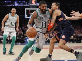 Boston Celtics guard Kyrie Irving (11) drives past New York Knicks guard Trey Burke, right, during the second half of an NBA basketball game in New York, Saturday, Feb. 24, 2018. Irving had 31 points to lead the Celtics in a 121-112 victory. Celtics forward Al Horford is at left.