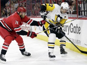 Carolina Hurricanes' Jaccob Slavin (74) and Pittsburgh Penguins' Sidney Crosby (87) chase the puck during the first period of an NHL hockey game in Raleigh, N.C., Friday, Feb. 23, 2018.