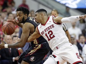 North Carolina State's Allerik Freeman (12) reaches for the ball while Florida State's P.J. Savoy dribbles during the first half of an NCAA college basketball game in Raleigh, N.C., Sunday, Feb. 25, 2018.