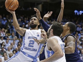 North Carolina's Joel Berry II (2) drives to the basket while Notre Dame's Elijah Burns defends as North Carolina's Luke Made (32) assists during the first half of an NCAA college basketball game in Chapel Hill, N.C., Monday, Feb. 12, 2018.