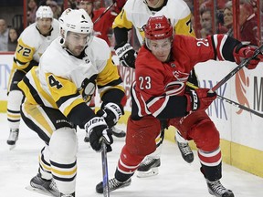 Carolina Hurricanes' Brock McGinn (23) and Pittsburgh Penguins' Justin Schultz (4) chase the puck during the second period of an NHL hockey game in Raleigh, N.C., Friday, Feb. 23, 2018.