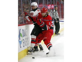 Carolina Hurricanes' Noah Hanifin (5) knocks New Jersey's Blake Pietila (56) off the puck during the first period of an NHL hockey game, Sunday, Feb. 18, 2018, in Raleigh, N.C.