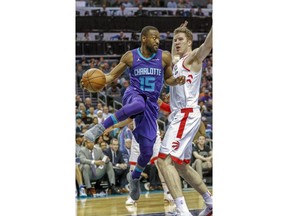 Charlotte Hornets guard Kemba Walker, left, passes around Toronto Raptors center Jakob Poeltl in the first half of an NBA basketball game in Charlotte, N.C., on Sunday, Feb. 11, 2018.