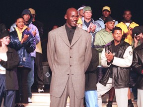 FILE - In this March 2,1999, file photo, Michael Jordan stands with a group of models at the Bellagio Hotel in Las Vegas where he previewed the Fall/Holiday 1999 Jordan collection, a sub-brand of Nike. By the 1980s, America finally publicly embraced the black athlete, looking past skin color to see athleticism and skill, rewarding stars with multimillion-dollar athletic contracts, movie deals, lucrative shoe endorsements and mansions in all-white enclaves. Who didn't want to be like Mike?