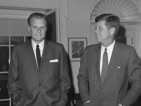 FILE - In this Dec. 12, 1961 file photo,  Evangelist Billy Graham, left, talks with President John F. Kennedy during a call at the the White House in Washington.   Graham, who transformed American religious life through his preaching and activism, becoming a counselor to presidents and the most widely heard Christian evangelist in history, has died. Spokesman Mark DeMoss says Graham, who long suffered from cancer, pneumonia and other ailments, died at his home in North Carolina on Wednesday, Feb. 21, 2018. He was 99. (AP Photo, File)