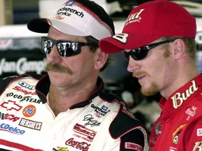 FILE - In this Friday, Feb. 9, 2001 file photo, NASCAR drivers Dale Earnhardt, left, and his son Dale Jr., stand together during a break in practice at the Daytona International Speedway in Daytona Beach, Fla. Dale Earnhardt Jr. worked with Goodyear to make a new commercial that honors his late father and shows the family history with the tire maker. The ad will debut in the season-opening Daytona 500, Sunday, feb. 18, 2018. Earnhardt is proud of the piece because of the way it celebrates his father.