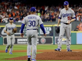 FILE - In this Oct. 18, 2017, file photo, Los Angeles Dodgers manager Dave Roberts walks out to pitcher Alex Wood during the sixth inning of Game 4 of baseball's World Series against the Houston Astros, in Houston. Major League Baseball is imposing stricter limits on mound visits in an effort to speed games but decided against 20-second pitch clocks for 2018. The new rules announced Monday, Feb. 19, 2018, include a general limit of six mound visits per nine-inning game without a pitching change, whether by a manager, coach or player.
