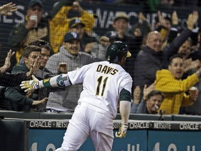 FILE - In this April 4, 2017, file photo, Oakland Athletics' Rajai Davis celebrates with fans as he scores on a throwing error after hitting a two-run triple off Los Angeles Angels' Bud Norris during the seventh inning of a baseball game in Oakland, Calif. The Athletics will expand protective netting between the stands and the playing field to the far ends of both dugouts ahead of the 2018 season.