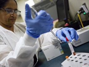 FILE - In this Friday, Feb. 9, 2018 file photo, lab technologist Sharda Modi tests a patient's swab for a flu infection at Upson Regional Medical Center in Thomaston, Ga. On Friday, Feb. 16, 2018, a report released by the Centers for Disease Control and Prevention shows the flu season may finally be leveling off.