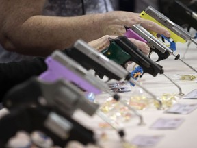 FILE- In this April 25, 2014, file photo, attendees look over a pistol display at the National Rifle Association's annual convention in Indianapolis. Hearing aid maker Starkey Hearing Technologies is joining other companies that have cut ties with the National Rifle Association after a school shooting in Parkland, Fla., on Feb. 14, 2018. Over a dozen companies including Metlife, Hertz, Avis, Enterprise, Best Western, Wyndham, United Airlines, and Delta, which have ended NRA partnerships since the shooting.