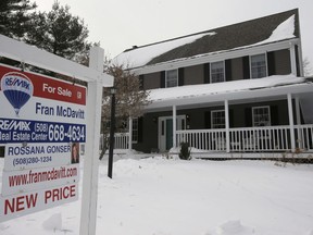 In this Monday, Jan. 8, 2018 photo a real estate for sale sign hangs in front of an existing home, in Walpole, Mass. On Wednesday, Feb. 21, the National Association of Realtors reports on January sales of existing homes.