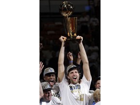 FILE - In this June 12, 2011, file photo, Dallas Mavericks' Dirk Nowitzki holds up the championship trophy after Game 6 of the NBA Finals basketball game against the Miami Heat in Miami. The Mavericks won 105-95 to win the series. Now in his 20th season, Nowitzki is comfortable with the idea that he led the Mavericks to their first championship and can try to help a younger core build toward making Dallas a title contender again.