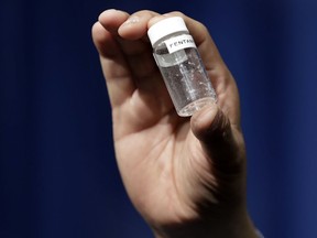 FILE - In this June 6, 2017 file photo, a reporter holds up an example of the amount of fentanyl that can be deadly after a news conference about deaths from fentanyl exposure, at DEA Headquarters in Arlington Va.  Some large law enforcement agencies have recently abandoned the routine chemical field tests  out of concern that officers could be exposed to opioids that can be absorbed through the skin or inhaled. Even a minute amount of the most potent drugs, such as fentanyl, can cause violent illness or death.