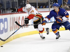 New York Islanders center Mathew Barzal (13) keeps Calgary Flames center Curtis Lazar (20) from the puck behind the net during the first period of an NHL hockey game in New York, Sunday, Feb. 11, 2018.