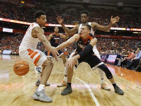 Virginia's Kyle Guy, center, passes the ball around Matthew Moyer, left, and Oshae Brissett, right, in the second half of an NCAA college basketball game in Syracuse, N.Y., Saturday, Feb. 3, 2018. Virginia won 59-44.