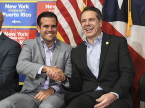 In this photo provided by New York Gov. Andrew Cuomo's office, Puerto Rico's Gov. Ricardo Rossello, left, shakes hands with Cuomo at a rally in the Bronx borough of New York, Saturday, Feb. 4, 2018. At the event, Cuomo stated that he was "ashamed" that this country failed to help Puerto Rico recover faster from last year's hurricane. About a third of Puerto Rico remains without power. (New York Governor's Office via AP)