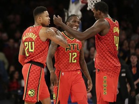 Atlanta Hawks' Kent Bazemore, left, celebrates his three-point basket with Taurean Prince, center, and Dewayne Dedmon during the last seconds of the second half of an NBA basketball game against the New York Knicks, Sunday, Feb. 4, 2018, in New York.