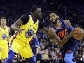 Oklahoma City Thunder's Paul George, right, is defended by Golden State Warriors' Draymond Green during the first half of an NBA basketball game Saturday, Feb. 24, 2018, in Oakland, Calif.