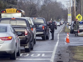 An official talks with a motorist outside Jackson Township Middle School, Tuesday, Feb. 20, 2018 in Massillon, Ohio. A school official in Ohio says a middle school student apparently shot himself after bringing a gun to school. Police say Jackson Middle School, near Massillon, is on lockdown Tuesday and that the students and staff are safe.