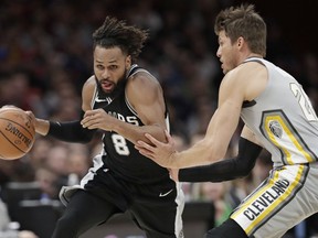 San Antonio Spurs' Patty Mills (8) is fouled by Cleveland Cavaliers' Kyle Korver (26) in the first half of an NBA basketball game, Sunday, Feb. 25, 2018, in Cleveland.