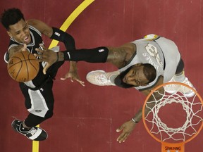 San Antonio Spurs' Dejounte Murray, left, shoots over Cleveland Cavaliers' LeBron James (23) in the first half of an NBA basketball game, Sunday, Feb. 25, 2018, in Cleveland.