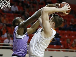 Kansas State forward Makol Mawien, left, gets his hand on the ball as Oklahoma State forward Mitchell Solomon, right, tries to shoot during the first half of an NCAA college basketball game in Stillwater, Okla., Wednesday, Feb. 14, 2018.
