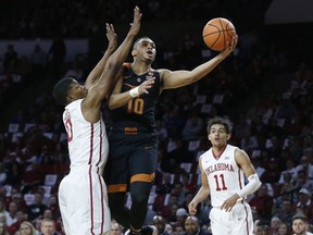 Texas guard Eric Davis Jr. (10) shoots between Oklahoma guard Christian James left, and guard Trae Young (11) in the first half of an NCAA college basketball game in Norman, Okla., Saturday, Feb. 17, 2018.