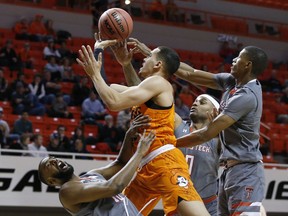 Oklahoma State guard Jeffrey Carroll, center, fouls Texas Tech guard Niem Stevenson, left, as he drives to the basket between Stevenson, guard Jarrett Culver, right, and forward Tommy Hamilton IV (0) during the first half of an NCAA college basketball game in Stillwater, Okla., Wednesday, Feb. 21, 2018.