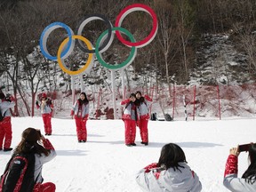 Volunteers take photos in front of the Olympic rings near the finish area during men's downhill training at the 2018 Winter Olympics in Jeongseon, South Korea, Friday, Feb. 9, 2018.