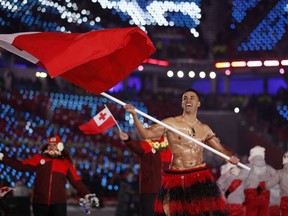 FILE - In this Feb. 9, 2018 file photo, Pita Taufatofua carries the flag of Tonga during the opening ceremony of the 2018 Winter Olympics in Pyeongchang, South Korea. Taufatofua has more on his mind than just trying to compete at the Pyeongchang Olympics this week. The 34-year-old cross-country skier is concerned about his homeland after it was hit by a cyclone which destroyed Parliament House as well as churches and homes.